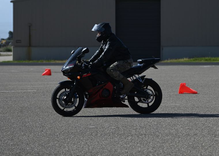 A rider leaning a motorcycle around cones on a training course