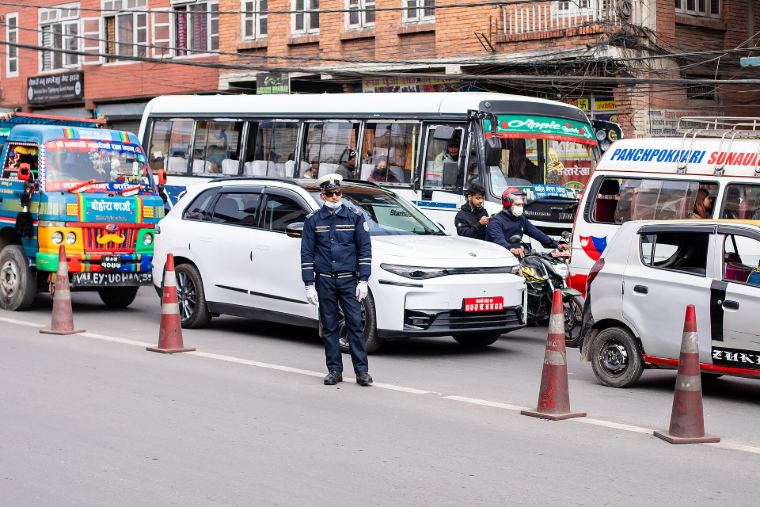 A traffic police officer directing cars and buses at a busy Kathmandu junction