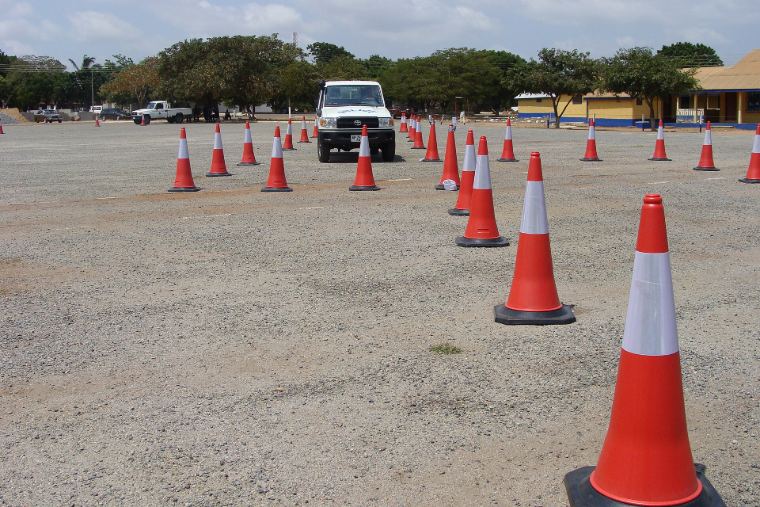 Orange traffic cones laid out in rows on a gravel driving practice ground
